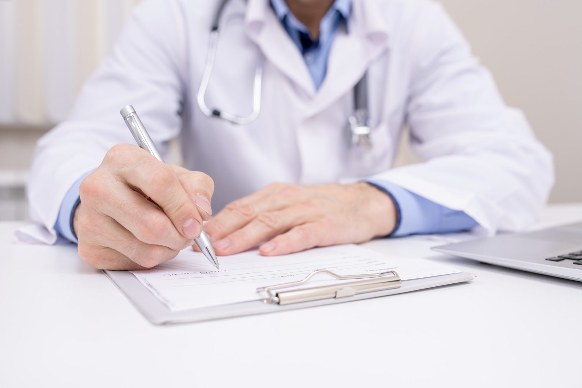 hand-of-professional-clinician-with-pen-over-clipboard-with-medical-document-e1598498443615.jpg
